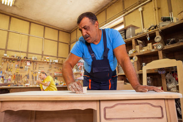 Indian carpenter making a wooden table. Removing rough surfaces on wood.