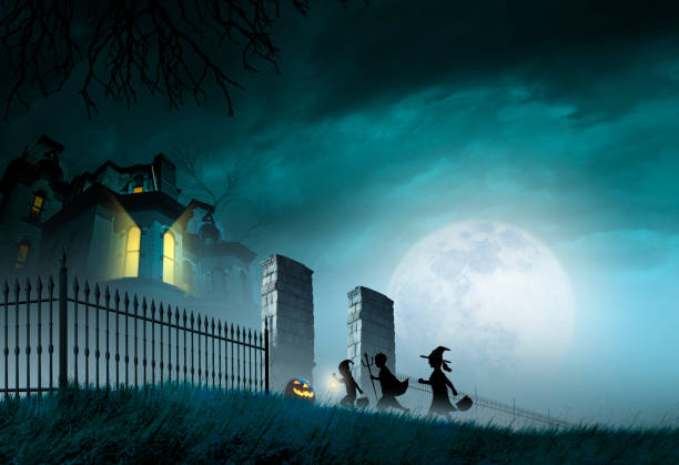 Three children trick or treating on Halloween night approach a haunted house as they pass by an illuminated jack o'lantern on their way through the gate.