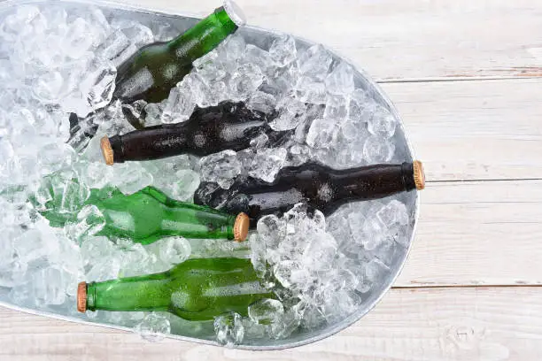 High angle view of a beer bucket filled with ice and assorted beer bottles. Horizontal format with copy space.