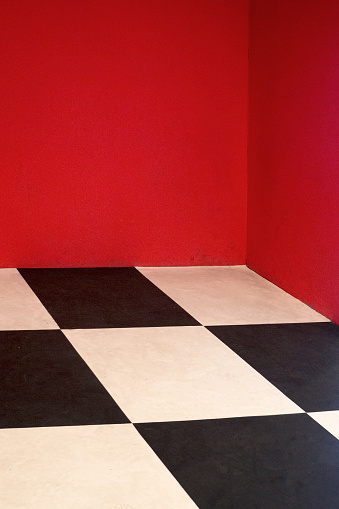 Empty room with Checkered floor and red painted wall.
