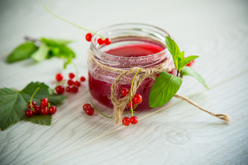 sweet summer jam from ripe red currants in a jar on a wooden table