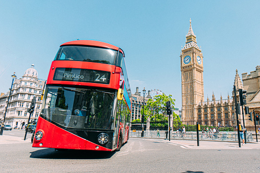 Iconic Red London Bus Turning in Front of London's Famous Clock Tower Featuring Big Ben Near the Westminster Palace in London