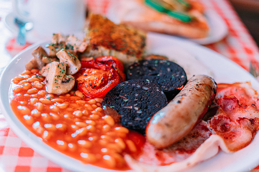 Traditional English Breakfast including a Cumberland-Style Sausage, Fried Egg, Bubble & Squeak, Bacon, Baked Beans, Black Pudding, Mushrooms, and Grilled Tomatoes
