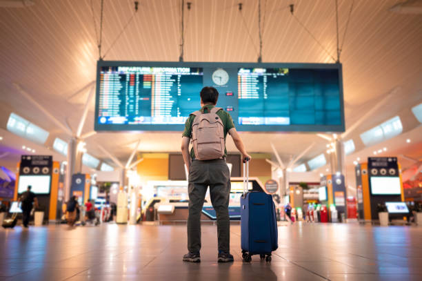 männlicher tourist mit blick auf die ankunfts- und abflugtafel am kuala lumpur international airport - ankunfts und abfahrtstafel stock-fotos und bilder