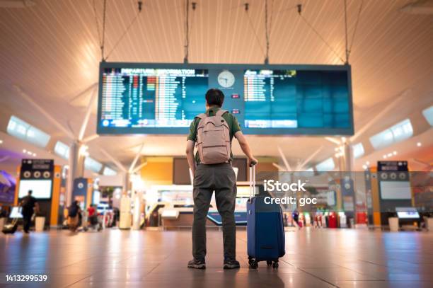 Male Tourist Looking At Arrival And Departure Board At Kuala Lumpur International Airport Stock Photo - Download Image Now