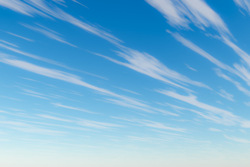 High altitude stretched cirrus clouds against a clear blue sky. 3D illustration rendering.