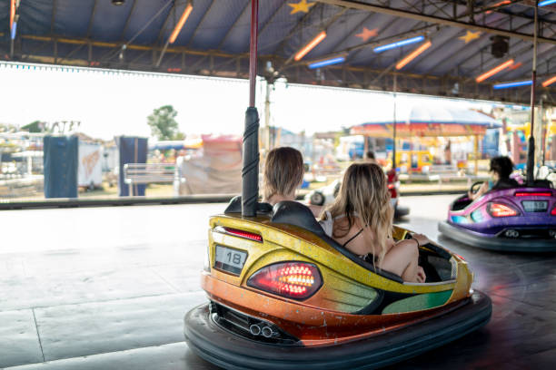 istock Two young girlfriends are laughing and shouting while riding a bumper car at amusement park 1413301798