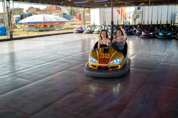 istock Two young girlfriends are laughing and shouting while riding a bumper car at amusement park 1413301834