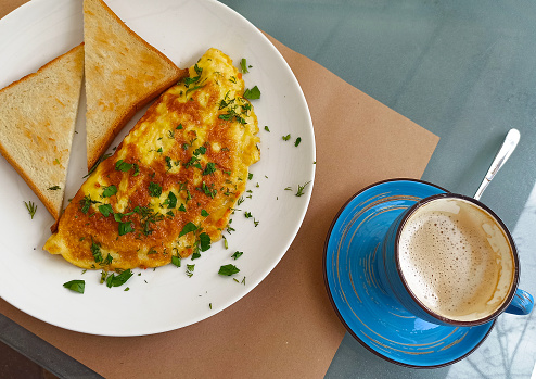 Breakfast served on the table, omelet with toasts and coffee