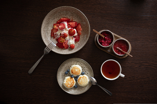 Tasty and healthy breakfast overhead view. Tea with jam, cheese pancakes, burrata salad with tomatoes