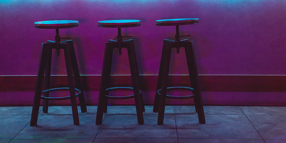 Chair in bar concept. Color neon light. Dark abstract background.