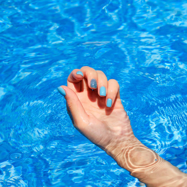 istock Female hands with bright manicure inside of water 1413318208