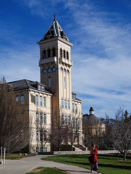 Woman on her phone walking from Old Main on the campus of Utah State University. Logan, Utah, USA-April 10, 2022:Young woman on her phone walking away from Old Main on the campus of Utah State University. utah state university stock pictures, royalty-free photos & images