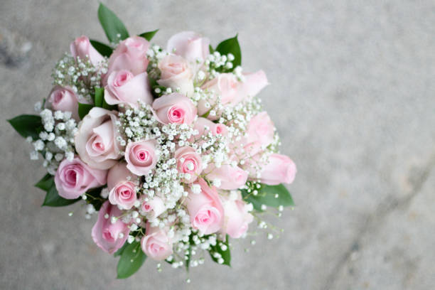 Bridal bouquet with pink roses and baby's breath. Cracked cement background