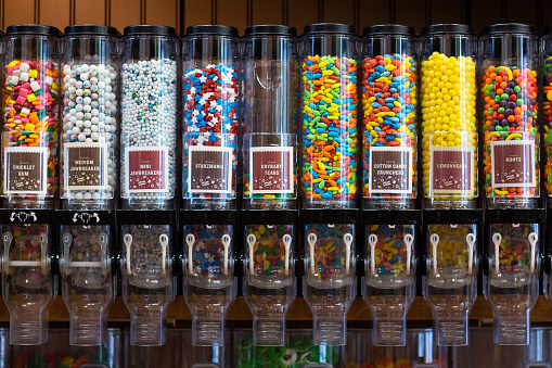 Several dispensers at a candy store, filled with brightly colored candy