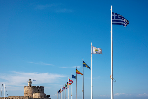 Old Saint Nicholas fortress and lighthouse in Mandraki Harbour at Rhodes, Greece. European Union Flags.