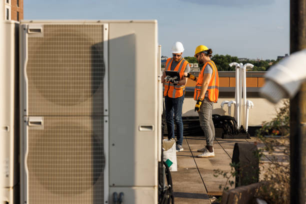 istock Teamwork for air-condition unit inspection on a rooftop. Supervisor and worker checking air condition system and logging results with a portable computer. 1413326472