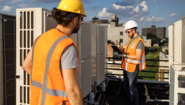 istock Aircondition units inspection on a rooftop. A portable computer is used by the supervisor and the worker to record the results of the air conditioning system checking. 1413326478
