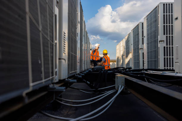 istock Aircondition units inspection on a rooftop. Supervisor and worker checking air condition system and logging results with a portable computer. 1413326486