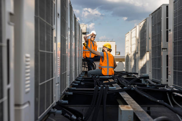 istock Aircondition units inspection on a rooftop. An air conditioning system is checked by the supervisor and a worker using a portable computer to record the results. 1413326487