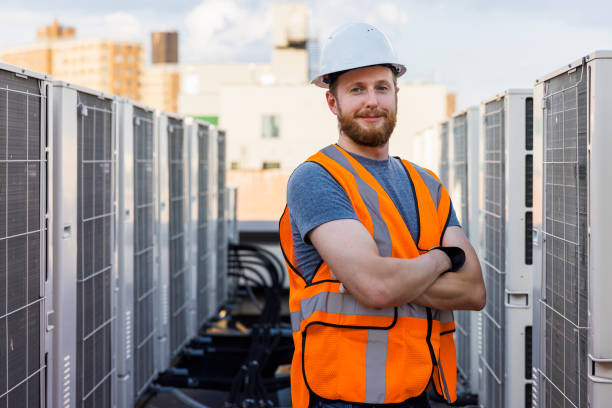 istock Technician, blue collar worker posing near roof-top air-conditioning units. 1413326515