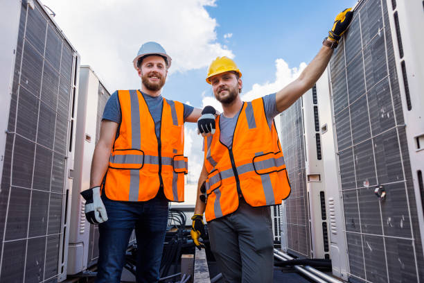 An engineer and a technician posing near the roof's air conditioners. stock photo