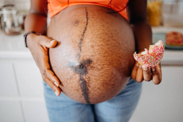 Pregnant woman holding doughnut with sugar sprinkles at home