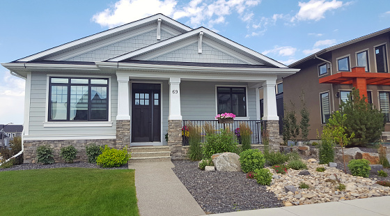Calgary, Alberta, Canada- July 3,2022:  Front view of new 21st century Craftsman shingle style  Bungalow. Replicated from early 20th century homes. Easy to care for front yard and garden. Next door to large modern day architecture.