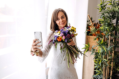 Woman takes a selfie with a bouquet of flowers she made