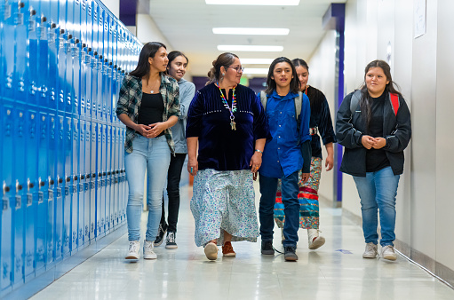 Niños de secundaria caminando por un pasillo junto a su maestro photo