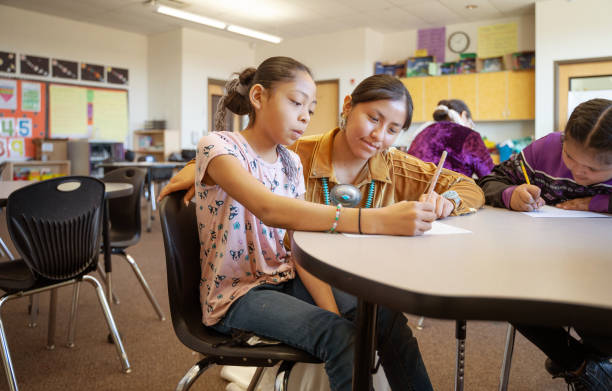 Young indigenous Navajo Young teacher checking her students class work stock photo