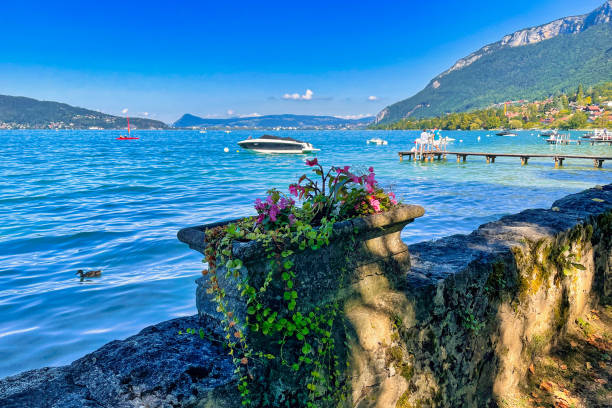Menthon saint Bernard, France - September 12 2021 : a classic stone flower pot with ivy on the edge of the board walk with view of the lake of annecy
