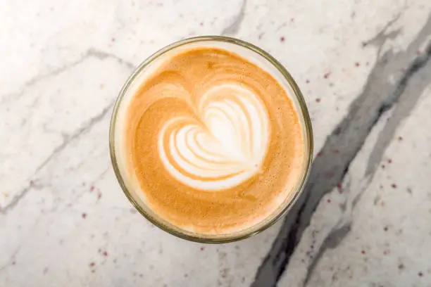 Photo of Cappuccino coffee with heart drawing on marble table top view