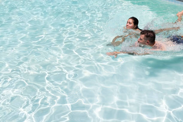 istock Young couple swim together in backyard pool 1413337698