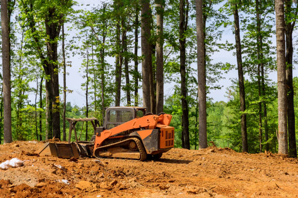 A construction industrial grader is used in the process of leveling the land to prepare it to be used for a new building in the construction industry stock photo
