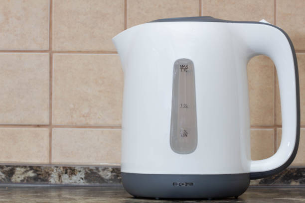 istock Electric kettle. White plastic electric kettle on the kitchen table against the background of beige tiles on the wall. Kitchen equipment. Boiling water for tea, coffee, hot drinks. Copy space for text 1413341399