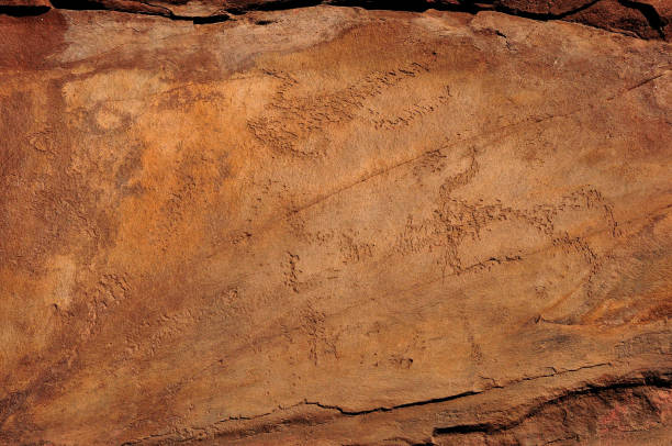 istock Flat red stone with ancient drawings of a hunting scene. 1413344551