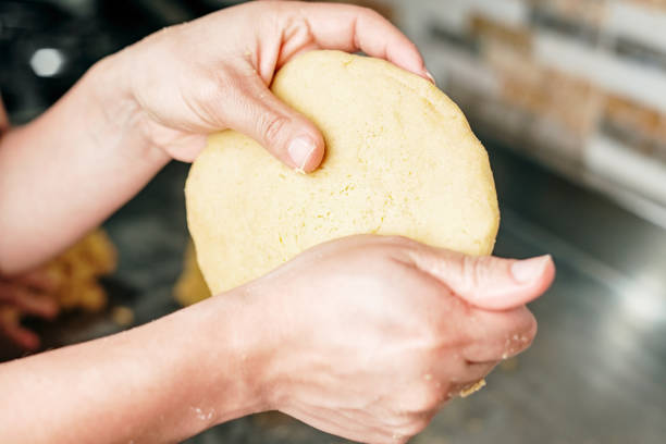 Unrecognizable woman making arepas paisas with her hands in the kitchen