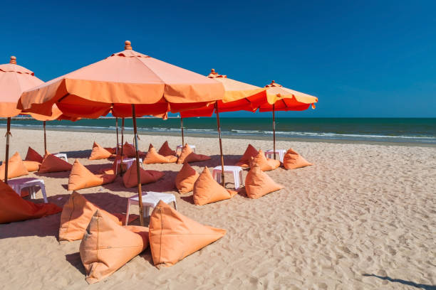 istock Orange bean bag chairs and parasols on summer sand beach 1413353622