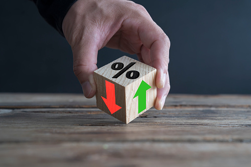 Businessman holds wooden blocks with percent and up or down arrow. Mortgage and loan rates. Interest rate, stocks, ranking. Business and finance concept.