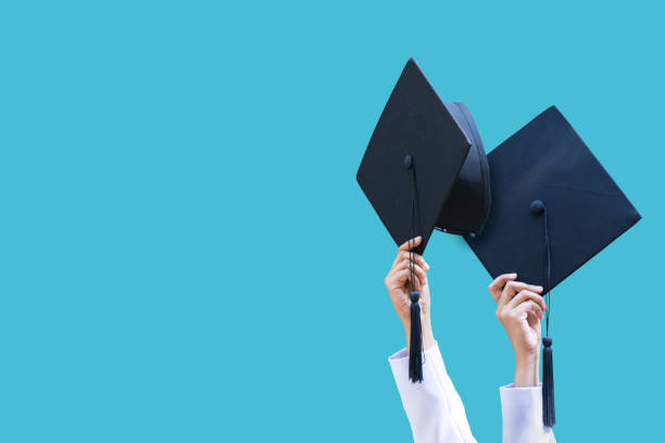 graduates student graduation caps thrown on a blue isolated - celebration imagens e fotografias de stock