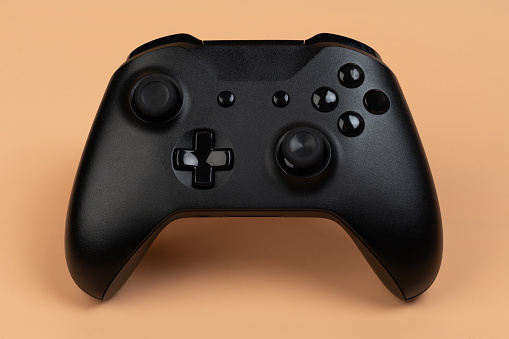 Black game controller front view isolated on brown background