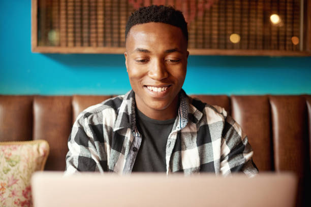 Creative entrepreneur with laptop browsing, reading and searching startup business ideas in cafe. Happy, confident man, proud remote blogger and student or freelancer with online blog in a restaurant