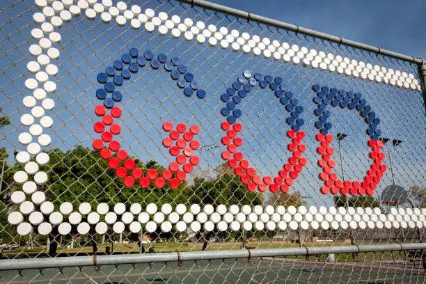 The word God spelled out on a fence with red white and blue round objects