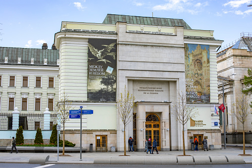 Madrid, Spain - 25th April 2022. A woman taking a photo of the Statue of Velázquez (1899, Aniceto Marinas Garcia) in front of the main gate of the Prado Museum in Madrid. There is a relief panel above the portico.