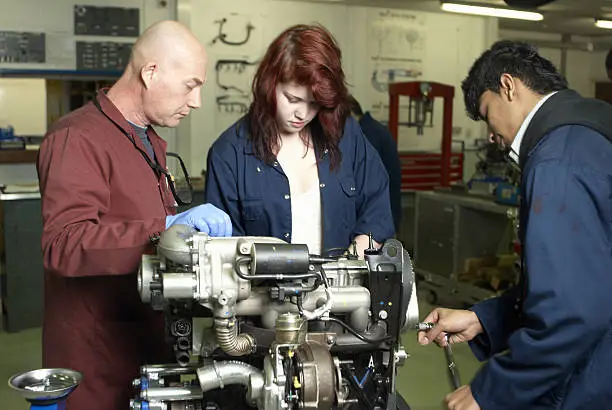 Photo of Teacher helping student with car engine