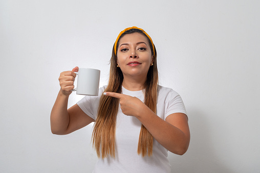 Portrait of woman showing a white cup. Person holding a cup of coffee, white background.