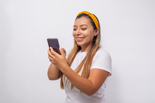 Portrait of a young woman writing on her cell phone. Portrait with white background.