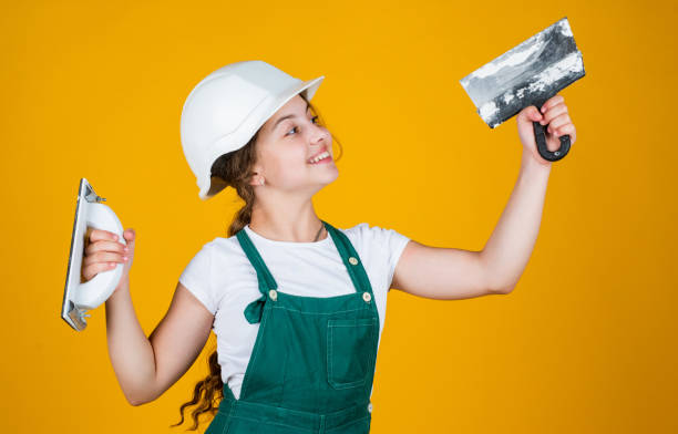 istock cheerful child laborer using building uniform and plastering spatula, equipment 1413379571