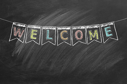 Hand drawn WELCOME text with bunting flags on blackboard.